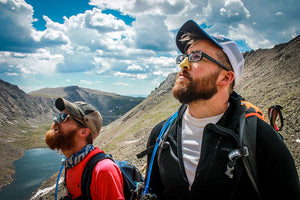 two men hiking wearing reef safe sunscreen on their nose looking up at the sun